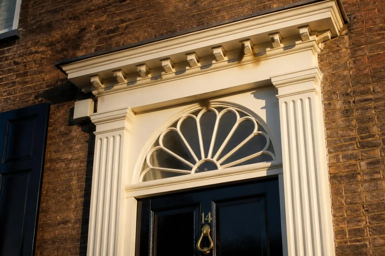 Limestone door surround, fanlight transom, and iron lantern on an Eastover brick facade
